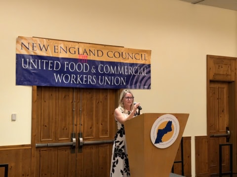 Woman speaking at a podium during a union meeting at UFCW 371 event.