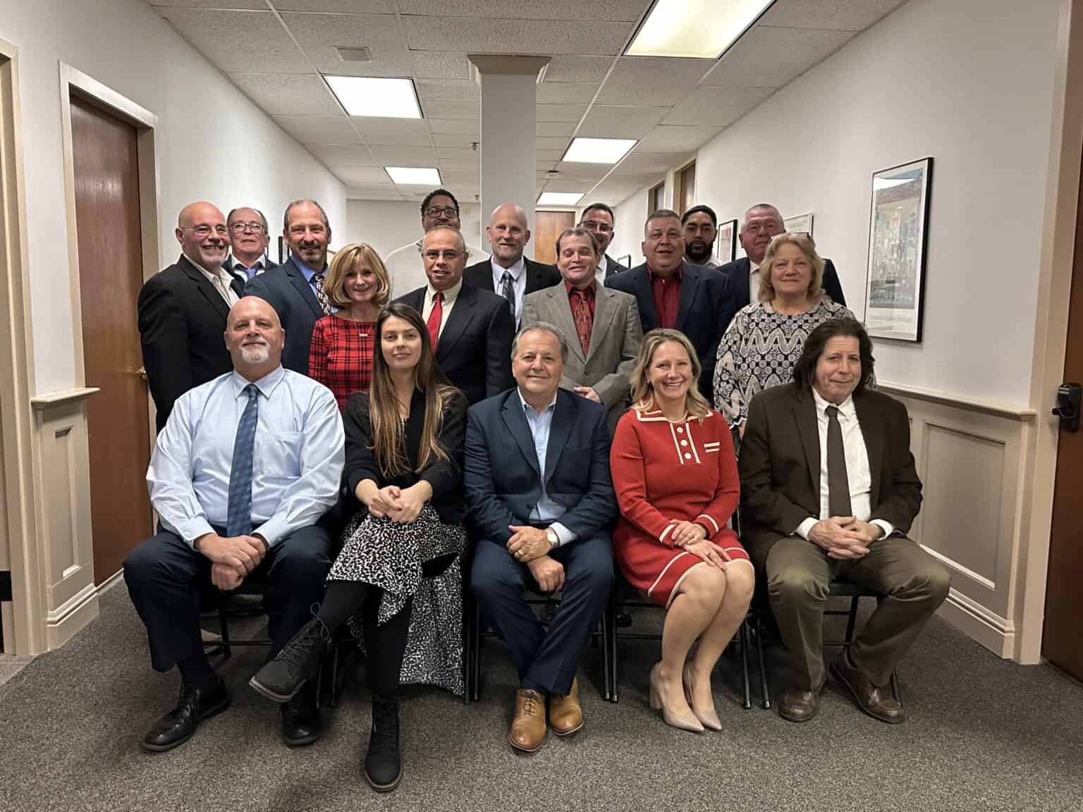 Group of professionals posing in an office hallway for a photo.