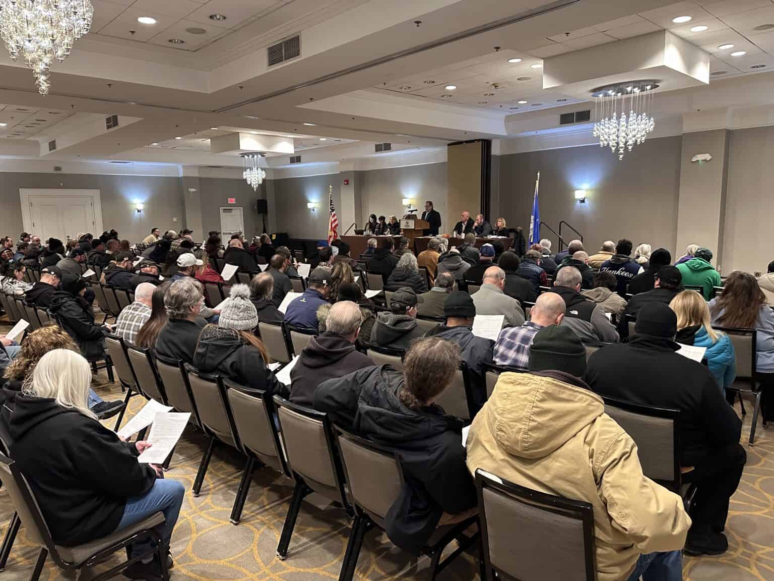 Union meeting with attendees listening to speakers at the podium in a large conference room.
