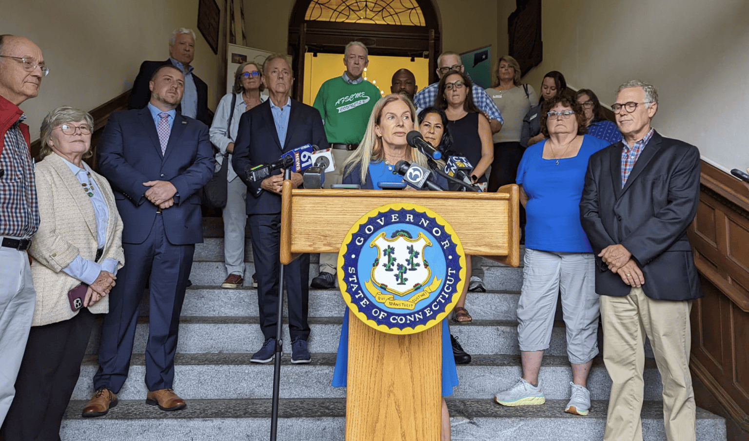 Group of diverse people at a press conference on courthouse stairs.