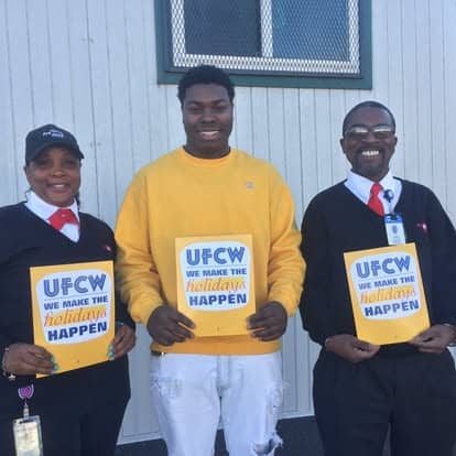 ProPark workers holding UFCW holiday signs outside a building.